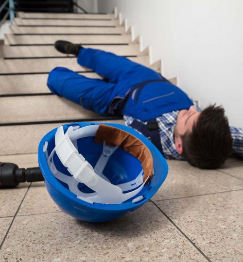 Unconscious Handyman Lying On Staircase With Helmet And Drill On Floor